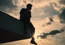 silhouette man sitting on edge of roof at sunset - photo by Khoa Võ on Pexels.com