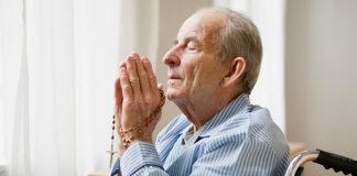 elderly man praying with rosary