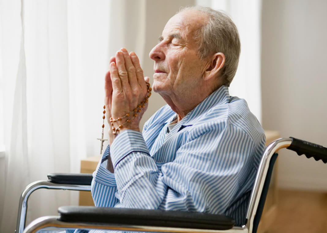 elderly man praying with rosary