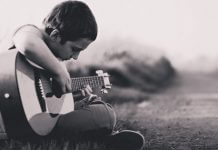 young man learning to play guitar
