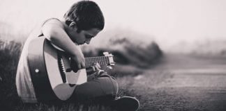 young man learning to play guitar