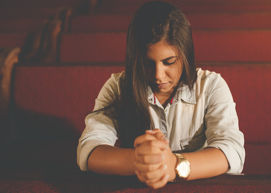 young woman praying in church - photo by Naassom Azevedo on Unsplash