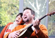 man playing guitar next to singing boy - ESB Professional/Shutterstock.com