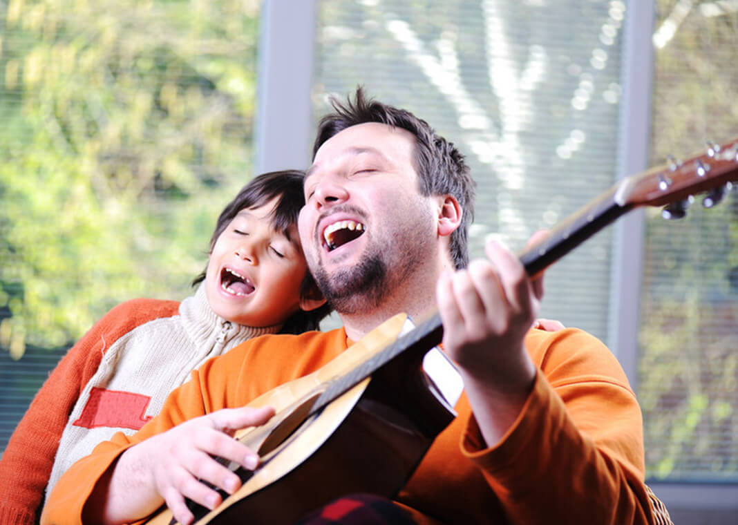 man playing guitar next to singing boy - ESB Professional/Shutterstock.com