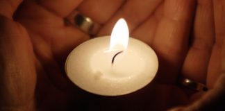 candle held in cupped hands