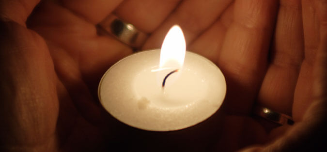 candle held in cupped hands