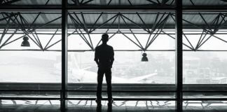 man staring out airport windows