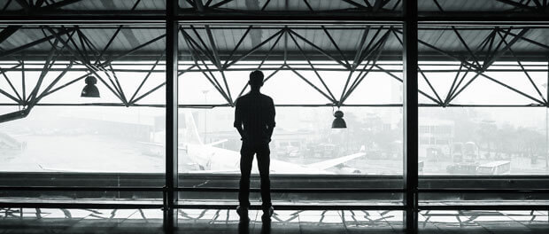 man staring out airport windows