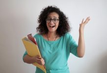 woman in green shirt wearing glasses and holding files, looking confused - photo by Andrea Piacquadio on Pexels