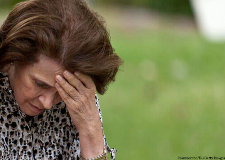 older woman sitting in pain with hand to her head - Juanmonino/E+/Getty Images
