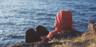 hooded figure sitting on island