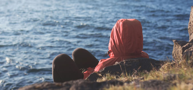 hooded figure sitting on island