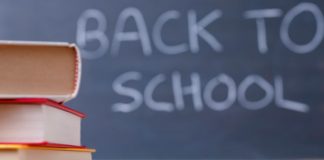 "Back to school" written on chalkboard with books in foreground