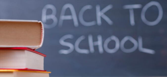 "Back to school" written on chalkboard with books in foreground