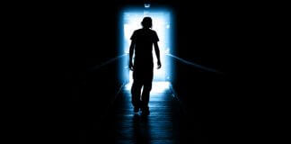 man walking through darkness to light