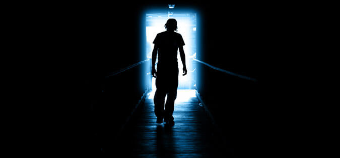 man walking through darkness to light