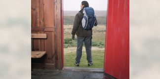 man standing in doorway ready for trip or hike