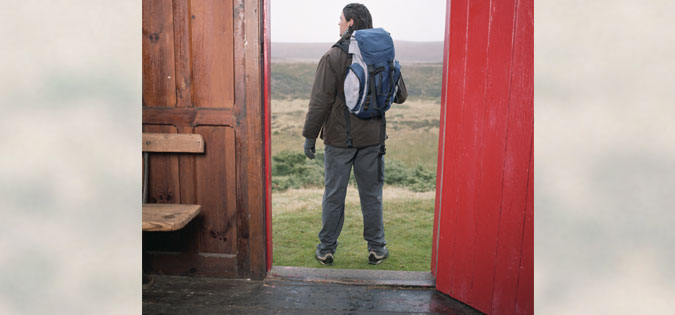 man standing in doorway ready for trip or hike
