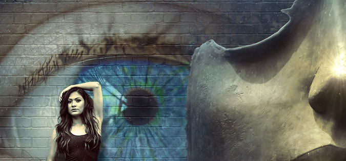 young woman standing in front of wall with eye painted on it