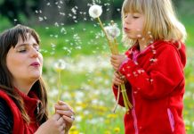 woman and young girl blowing dandelion seeds