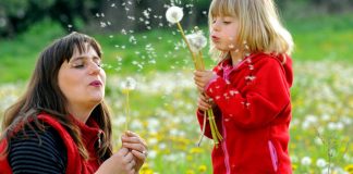woman and young girl blowing dandelion seeds
