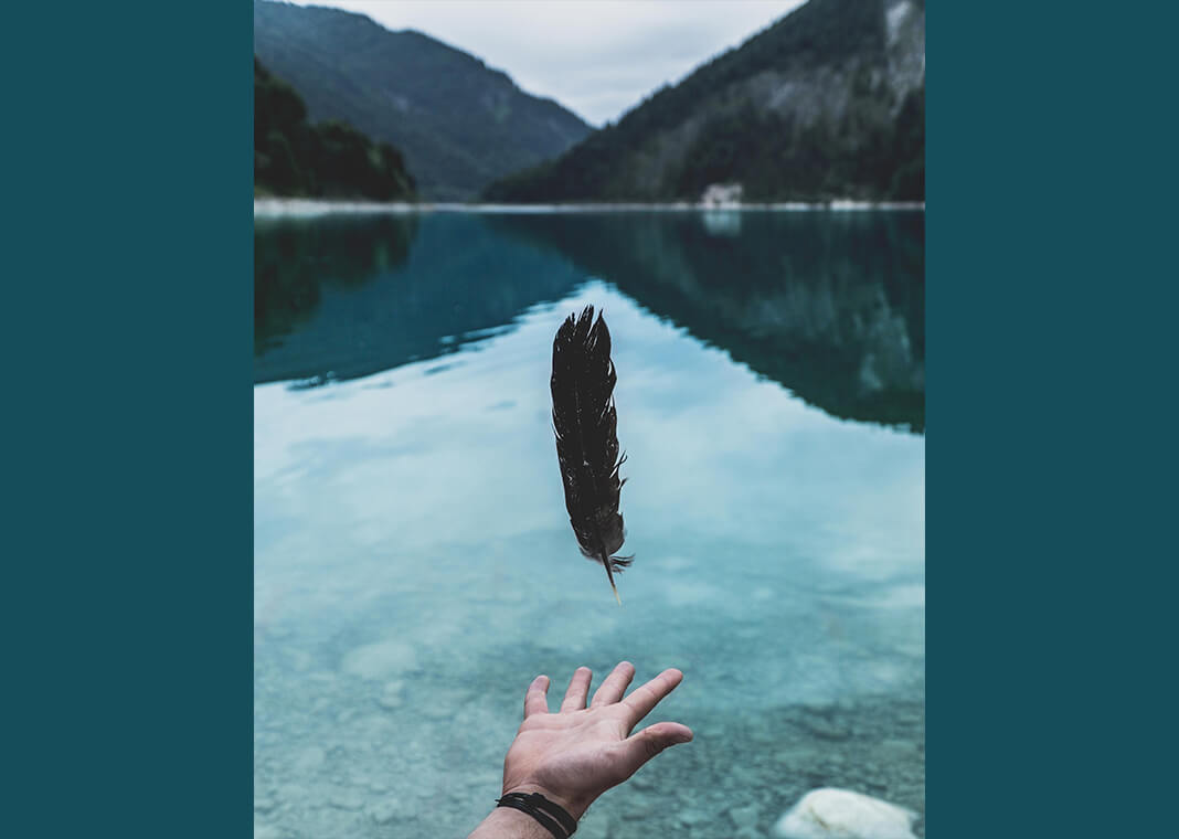 person letting go of feather - photo by Paul Gilmore on Unsplash