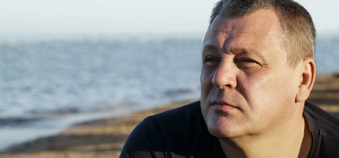 reflective man sitting near water