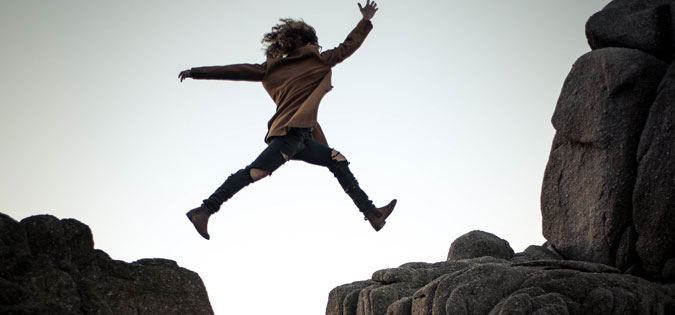 person shows courage by leaping over mountains