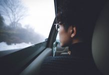 young man looking out car window