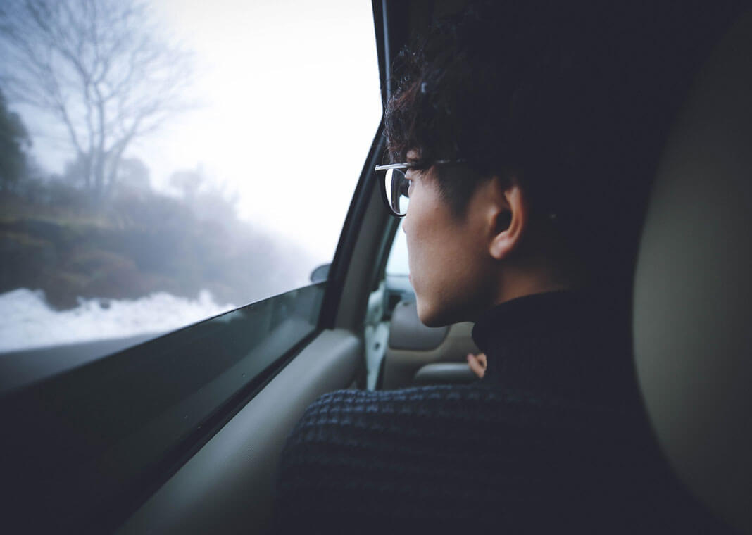 young man looking out car window