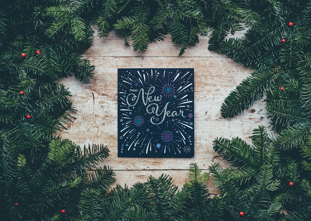 Happy New Year sign surrounded by evergreen branches - photo by Annie Spratt on Unsplash