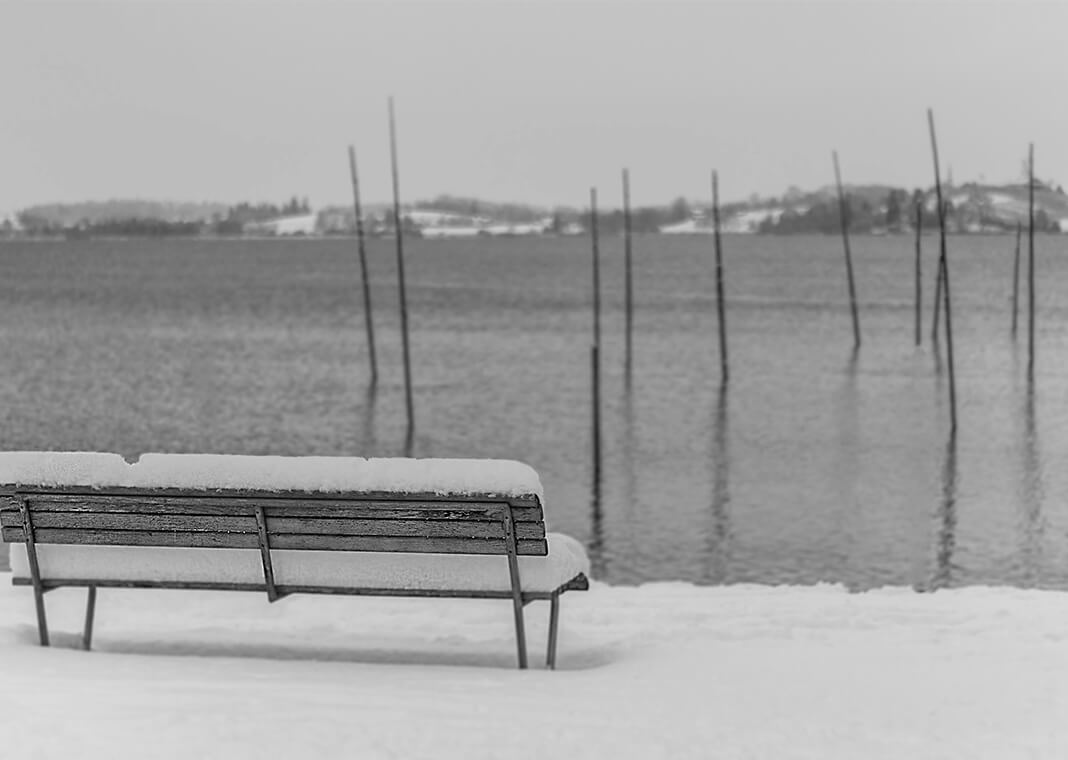 desolate winter scene of bench at water's edge - photo by Jan Huber on Unsplash