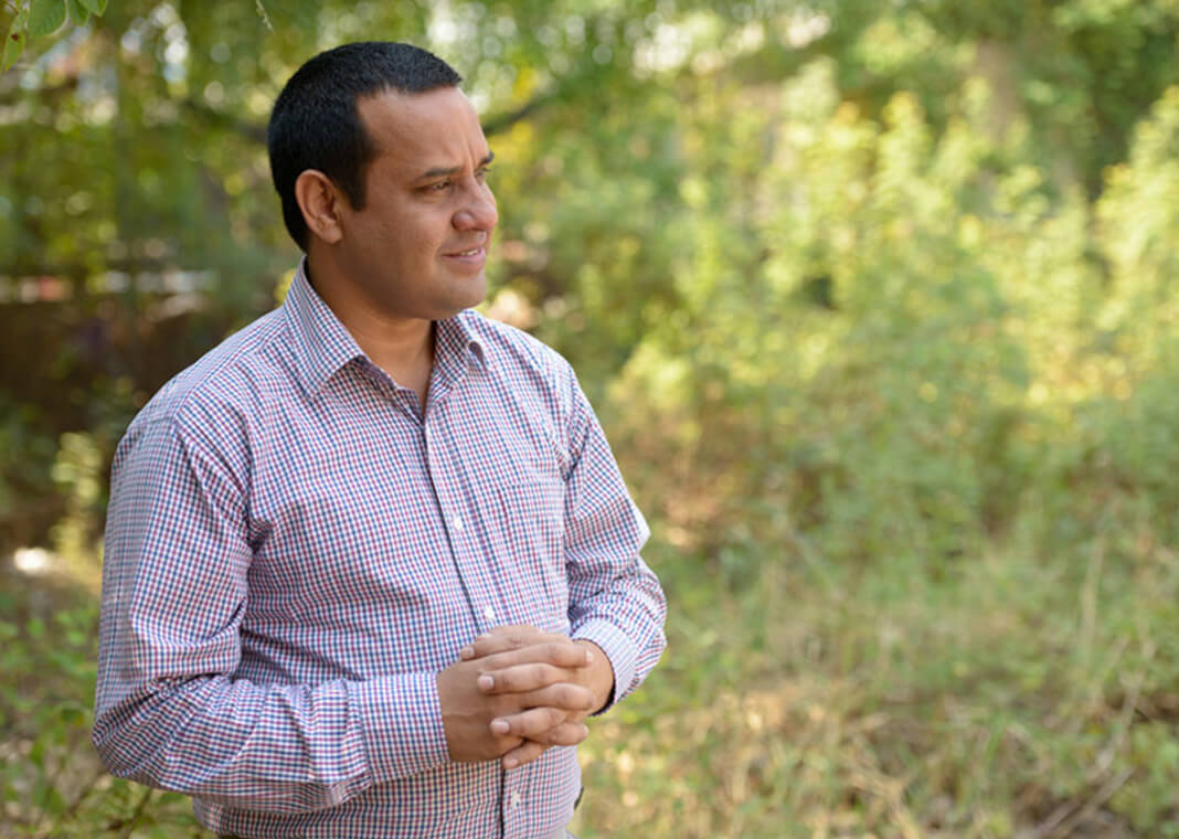 reflective man standing outside with hands folded