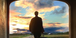 man leaving with suitcase to walk into sunrise over path - photo by Mantas Hesthaven on Unsplash