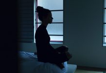 woman sitting on bed in darkness - photo by Ben Blennerhassett on Unsplash