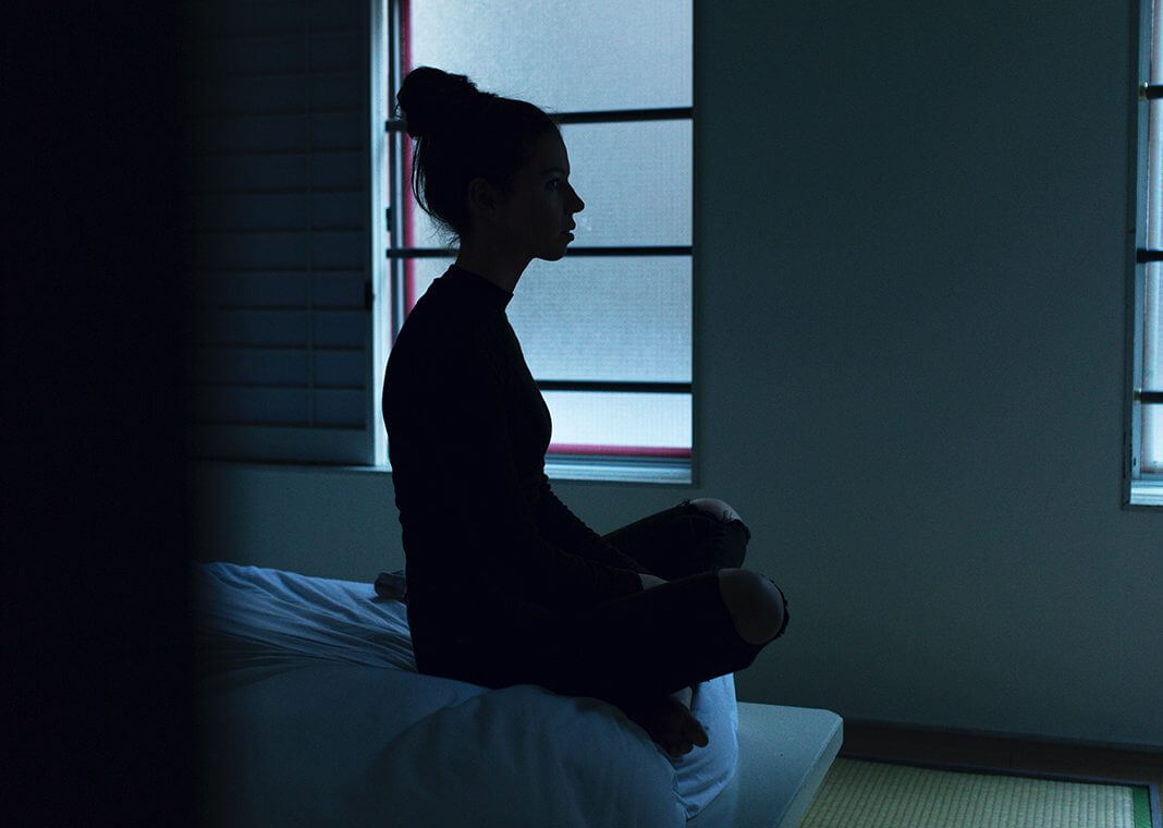 woman sitting on bed in darkness - photo by Ben Blennerhassett on Unsplash