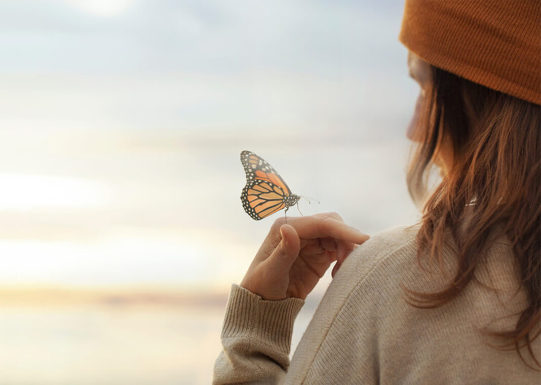 butterfly on woman's hand - Cristina Conti/Shutterstock.com