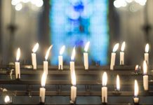 candles in front of blurry stained glass window - ImageJournal-Photography/Moment/Getty Images