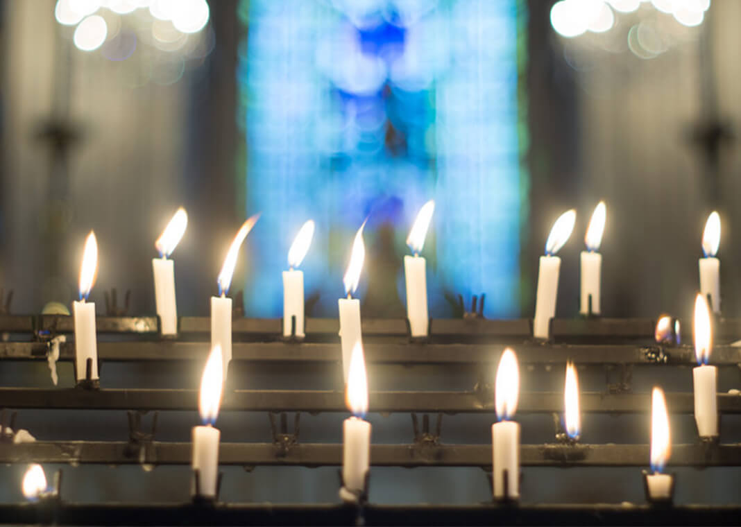 candles in front of blurry stained glass window - ImageJournal-Photography/Moment/Getty Images