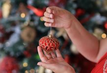 woman holding Christmas ornament - photo by Valeria Boltneva on Pexels