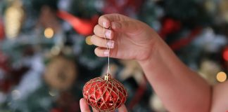 woman holding Christmas ornament - photo by Valeria Boltneva on Pexels