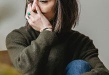 depressed woman sitting with hand over face - photo by Liza Summer via Pexels