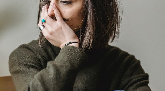 depressed woman sitting with hand over face - photo by Liza Summer via Pexels