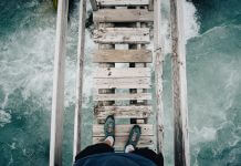 fearless person standing on wooden bridge over raging waters - photo by Benjamin Davies on Unsplash