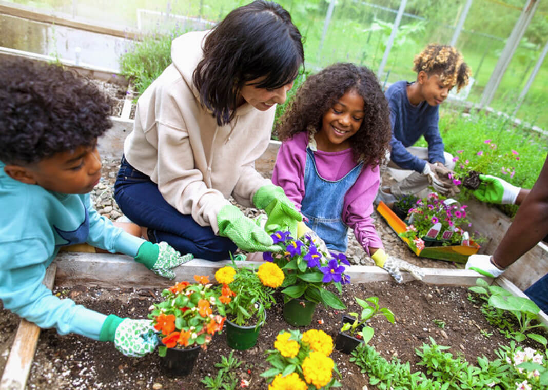 children gardening with help of adult woman - © Shannon Fagan - FangXiaNuo/E+/Getty Images