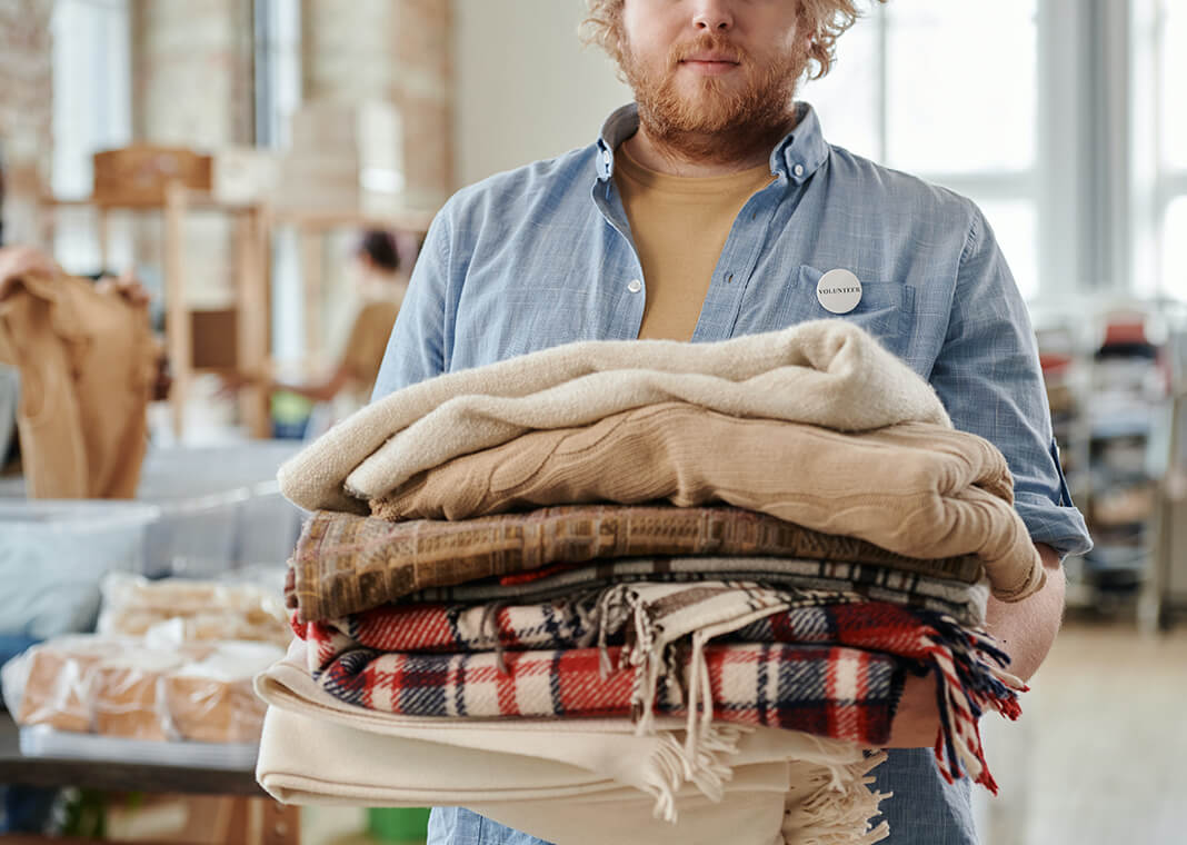 volunteer standing with armful of blankets - photo by Julia M. Cameron on Pexels
