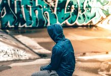 person sitting near graffiti wall - photo by Warren on Unsplash