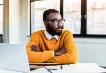 man sitting at computer with arms folded - LightFieldStudios/iStock/Getty Images