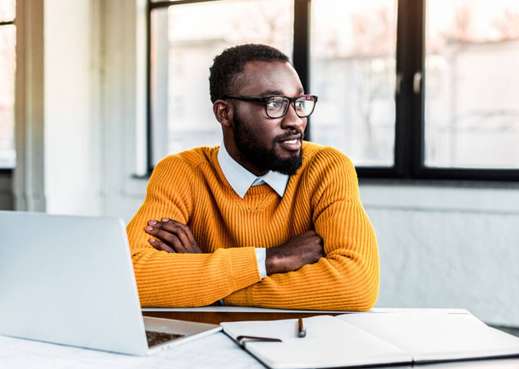 man sitting at computer with arms folded - LightFieldStudios/iStock/Getty Images