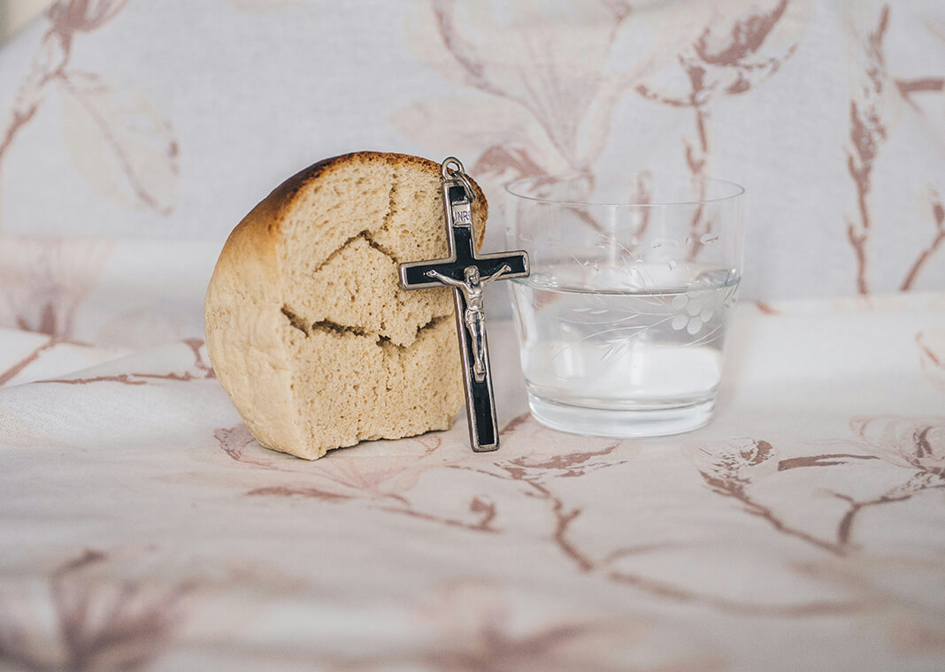 bread, water, and crucifix - photo by Kamil Szumotalski on Unsplash